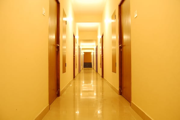 A long, narrow hallway with wooden doors on both sides, leading to a staircase at the end.