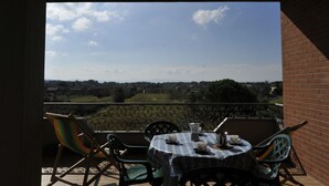 A balcony with a table set for two, overlooking a scenic landscape.
