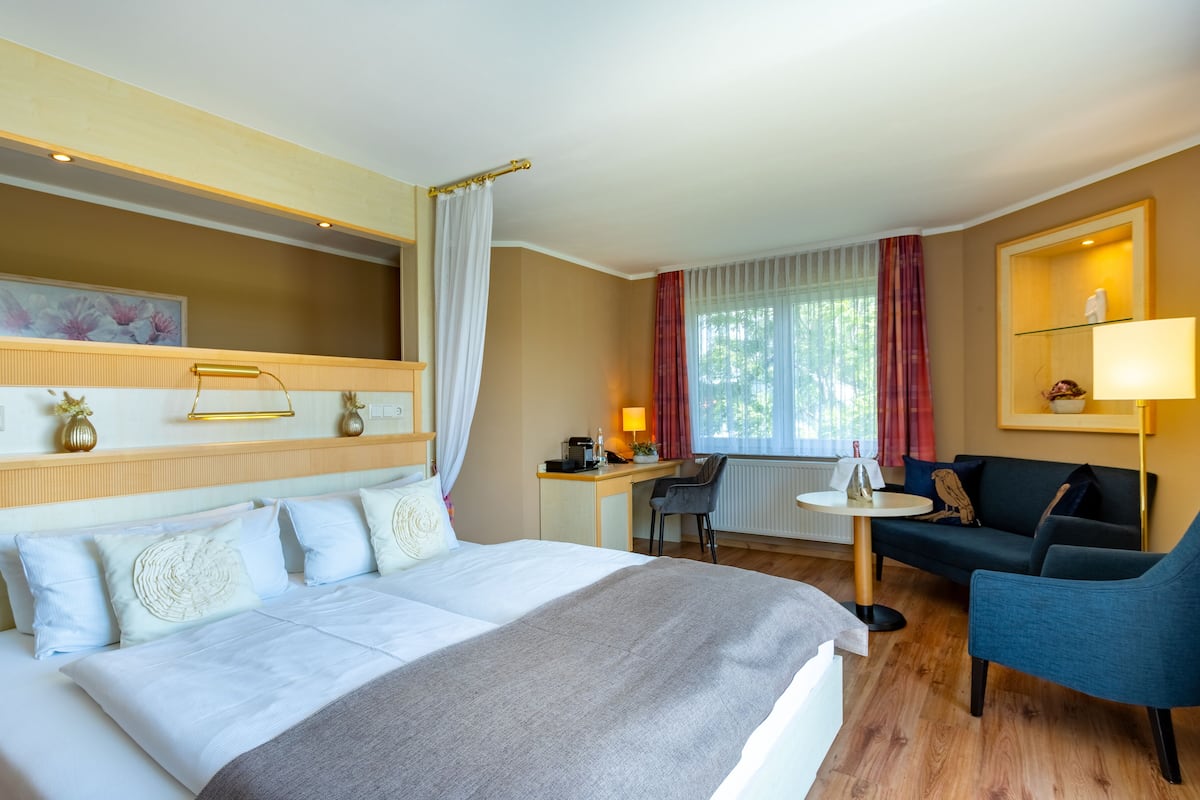 Une chambre d’hôtel comprenant un lit, un bureau, une chaise, un canapé et une petite table.