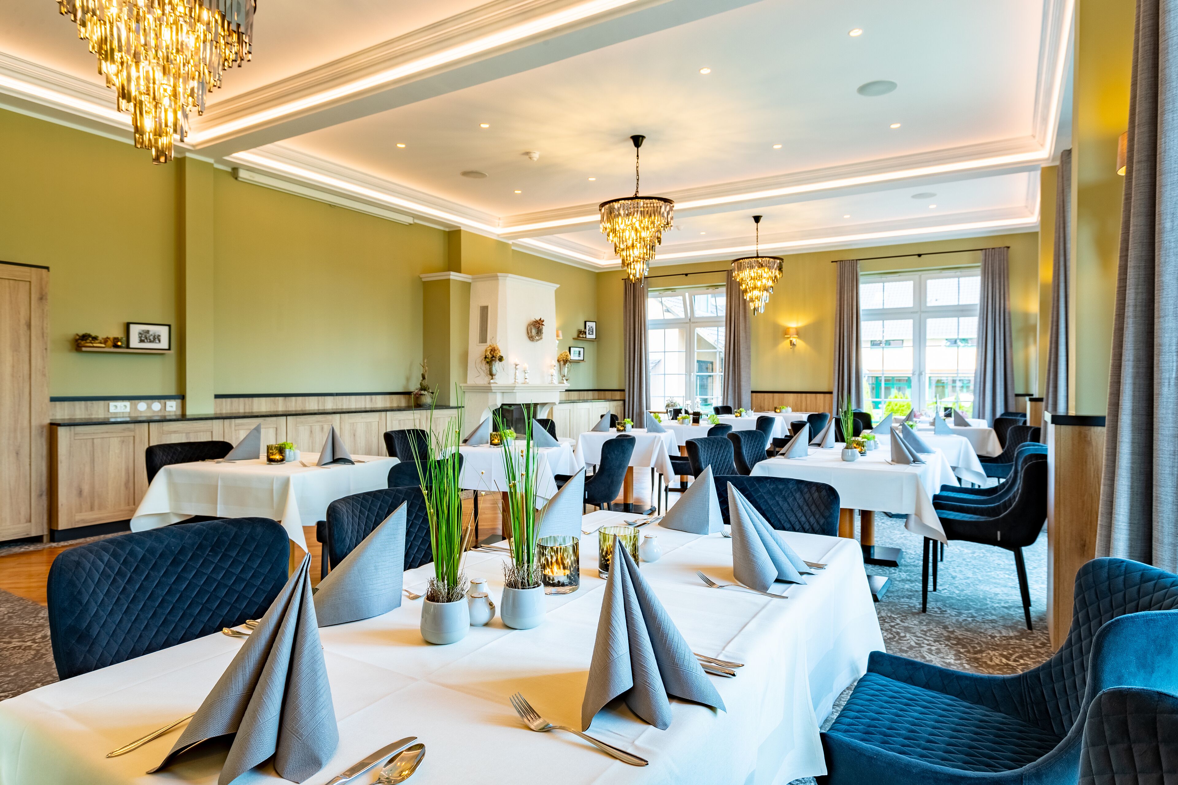 Un restaurante con mesas dispuestas para comer, con candelabros y plantas en macetas.