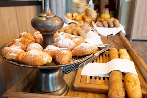 Una mesa de buffet con diversas opciones de panadería, incluyendo pasteles y pan.