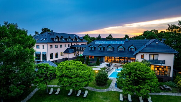A large, modern hotel with multiple buildings, a swimming pool, and well-maintained gardens.