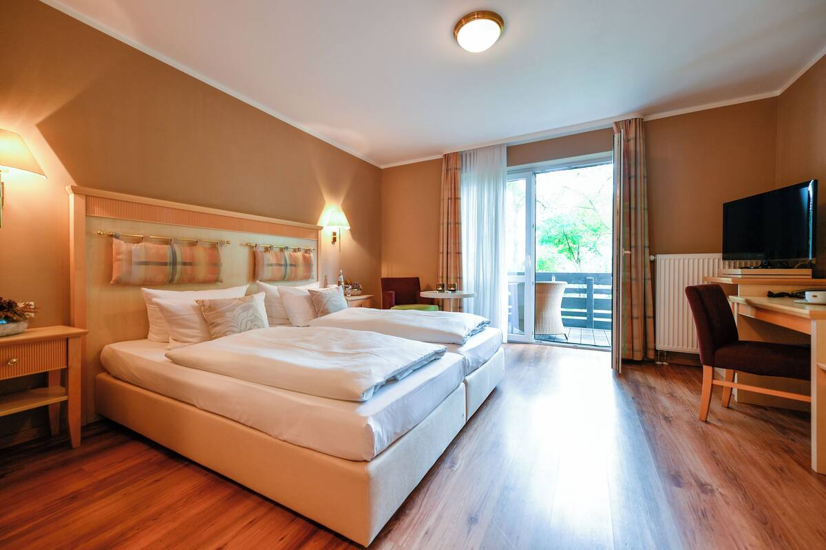 Une chambre d’hôtel avec deux lits, un bureau, une chaise, une télévision et une vue sur l’extérieur.