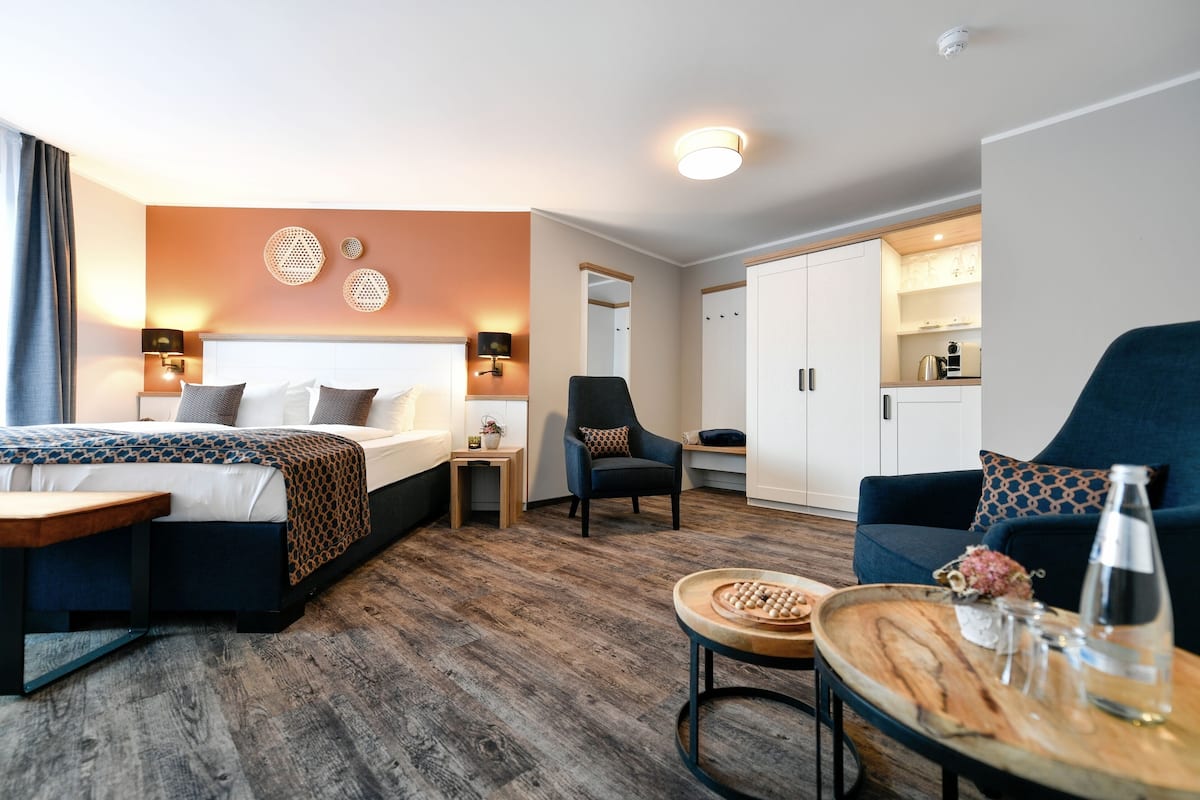 Une chambre d’hôtel comprenant un lit, un canapé, une petite table et une kitchenette.