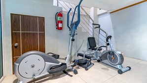 A gym with exercise equipment, a fire extinguisher, and a staircase. - Oun Residence (Hat Yai)