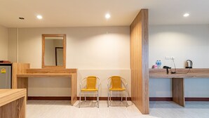 A modern kitchen with wooden countertops, two yellow chairs, a large mirror, and a built-in coffee machine. - Oun Residence (Hat Yai)
