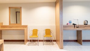 A hotel room with a wooden desk, two yellow chairs, a mirror, and a wooden partition. - Oun Residence (Hat Yai)