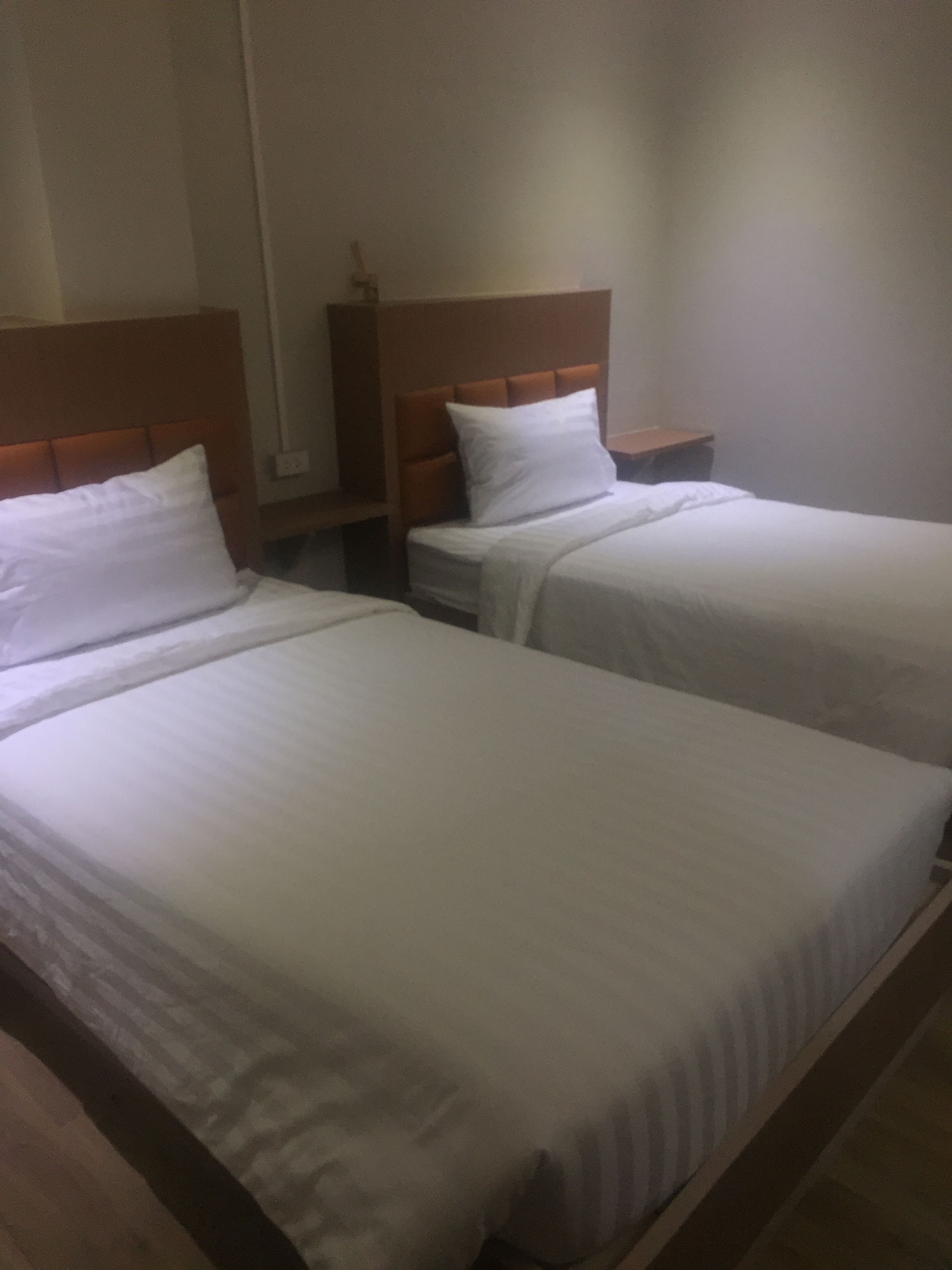 Two single beds with wooden headboards and white bedding in a hotel room.