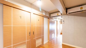 A corridor with wooden lockers, a wooden floor, and a grey wall. - Oun Residence (Hat Yai)