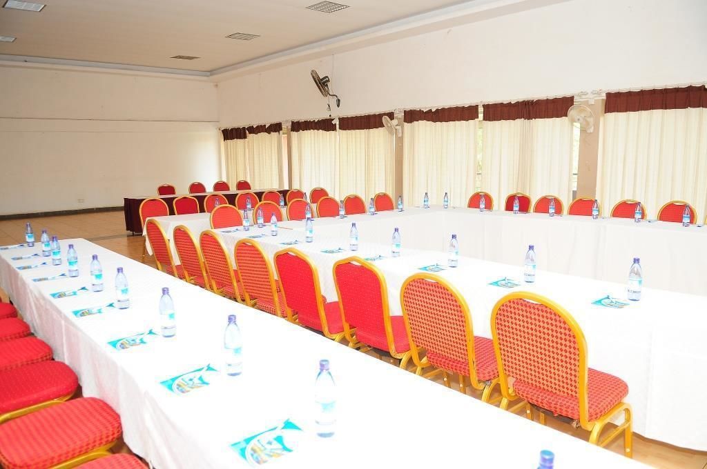 A conference room with a long table, red chairs, and water bottles.