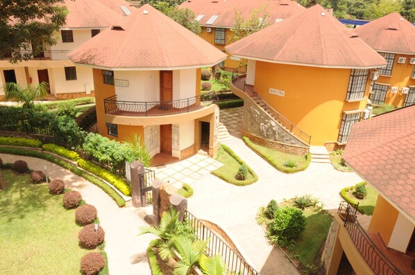 A courtyard with multiple buildings, each with a red-tiled roof and balconies. - Silver Springs Hotel Uganda (Kampala)