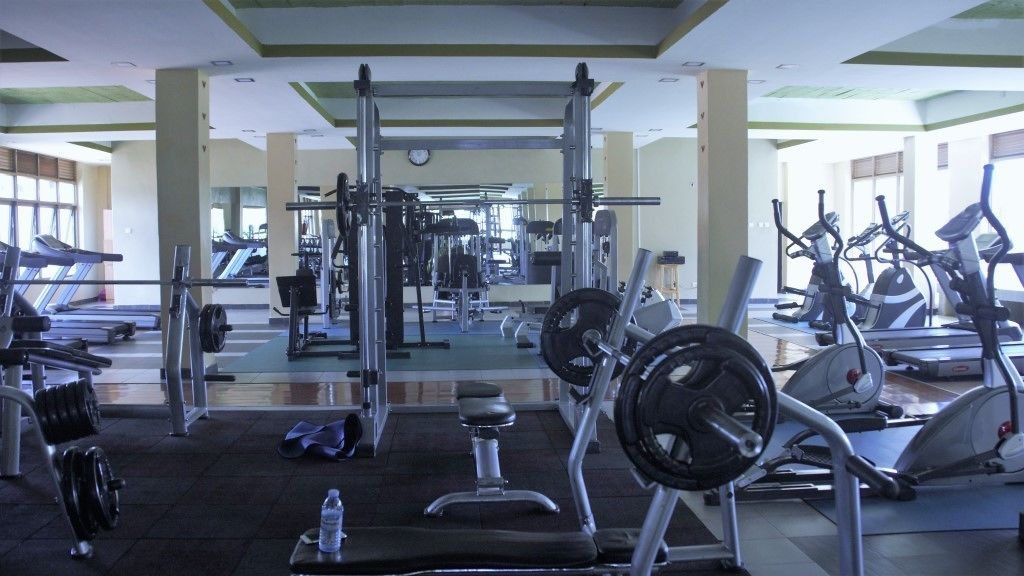 Una palestra con diverse attrezzature per l'allenamento, tra cui tapis roulant, macchinari per pesi e pesi liberi.