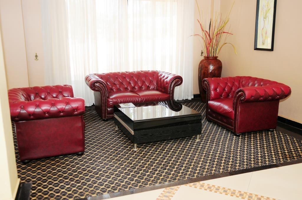 Une pièce comprenant trois canapés en cuir rouge disposés autour d’une table basse noire.