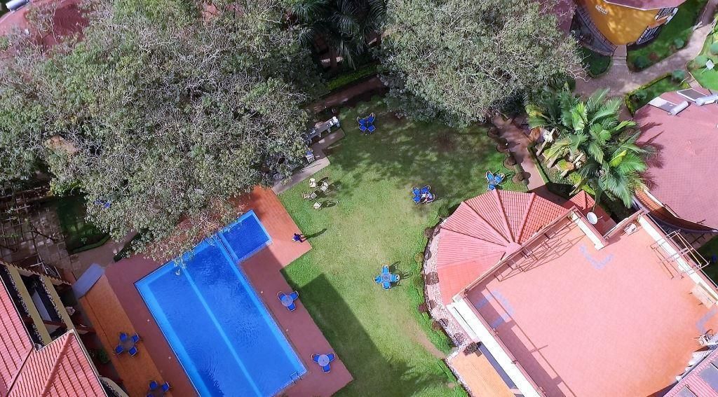 An aerial view of a hotel with a swimming pool, outdoor seating, and lush greenery.