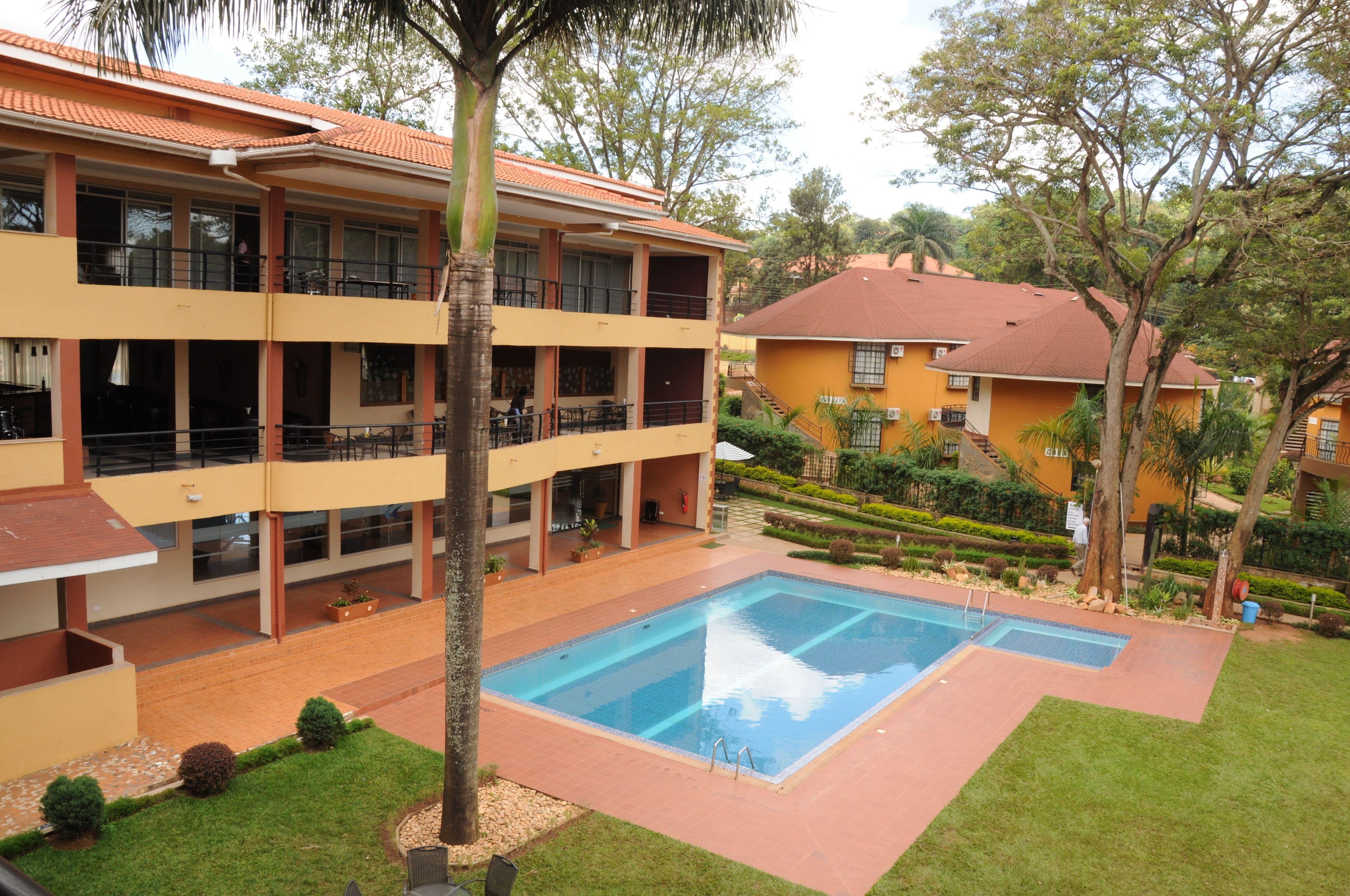 A hotel with a swimming pool, multiple balconies, and a well-maintained garden.