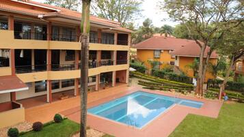 A hotel with a swimming pool, multiple balconies, and a well-maintained garden.