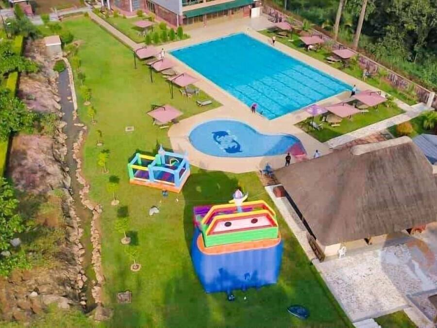 Vue aérienne d’un complexe hôtelier comprenant une grande piscine, un espace de jeux pour enfants et un petit bâtiment.