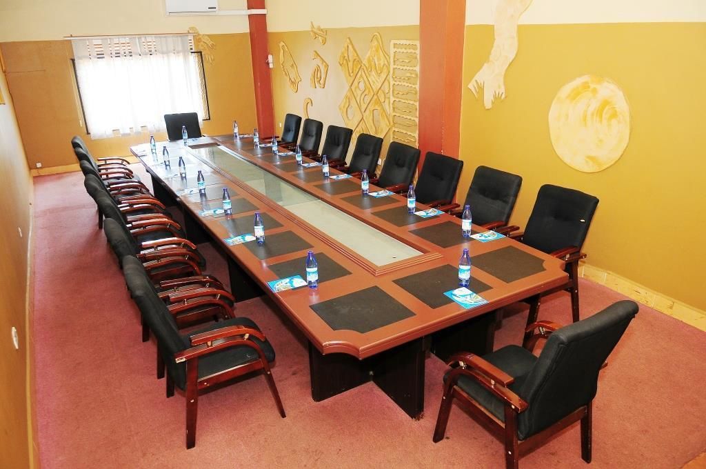A conference room with a long table, black chairs, and water bottles.