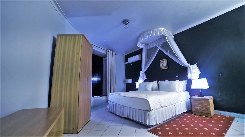 Um quarto com cama, mesa de cabeceira e criado-mudo.