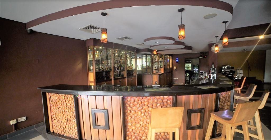 A bar area with a curved counter, wooden paneling, and hanging pendant lights.