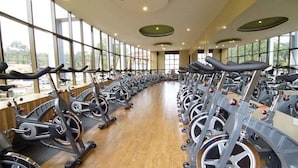 A gym with rows of stationary bikes, large windows, and a wooden floor. - Silver Springs Hotel Uganda (Kampala)