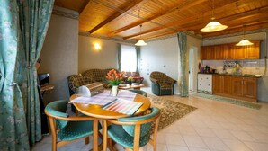 A cozy living room with a wooden ceiling, a dining area with a table and chairs, and a kitchen area with wooden cabinets and a sink. - Pine Wood Apartment 8 (Zalakaros)