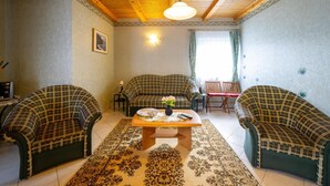 A cozy living room with a checkered sofa set, a wooden coffee table, and a patterned rug. - Pine Wood Apartment 8 (Zalakaros)