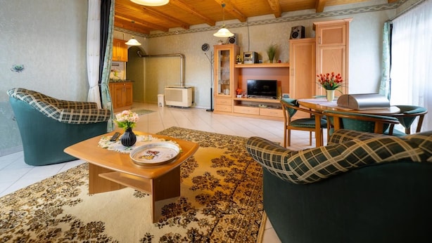 A cozy living room with a sofa, a coffee table, and a TV. There is a wooden ceiling and a window with curtains. - Pine Wood Apartment 8 (Zalakaros)
