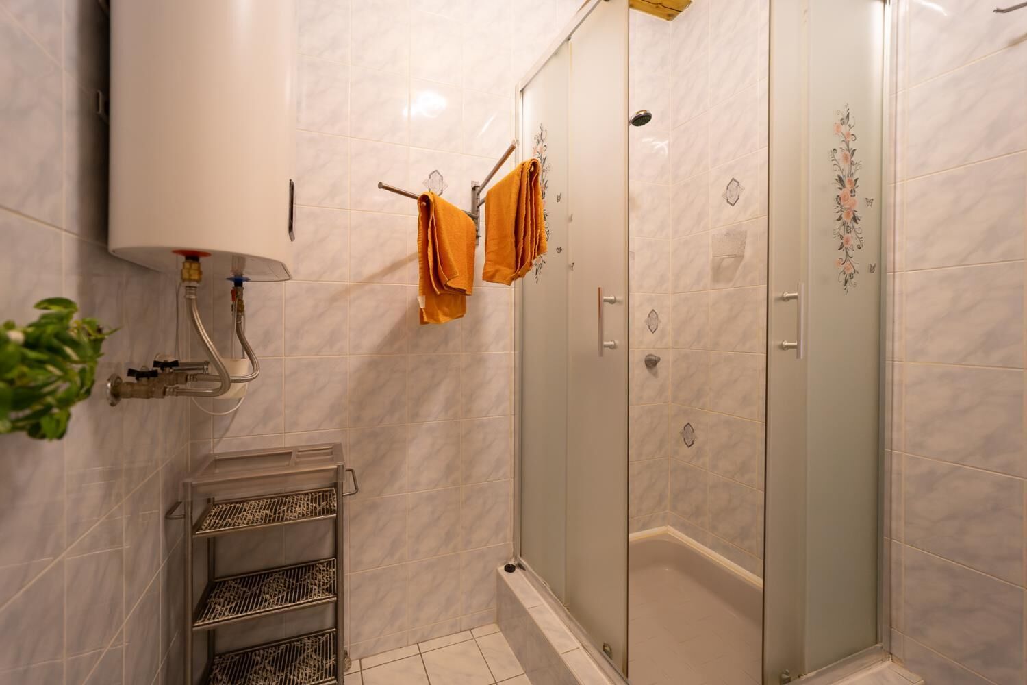 Un baño moderno con ducha acristalada, inodoro empotrado y toallero con dos toallas.
