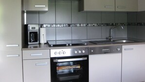 Una cocina moderna con horno empotrado, cafetera y pileta de acero inoxidable.