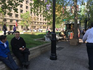 A public square with benches, a street lamp, and a building in the background. - La Moneda House (Santiago)