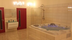 Un baño con una bañera grande, cabina de ducha con paredes de vidrio y tocador con espejo.