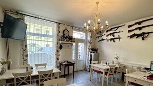 Comedor con mobiliario blanco, una araña y rifles colgados en la pared.