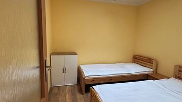 Una habitación con dos camas de madera, un armario y un tragaluz.