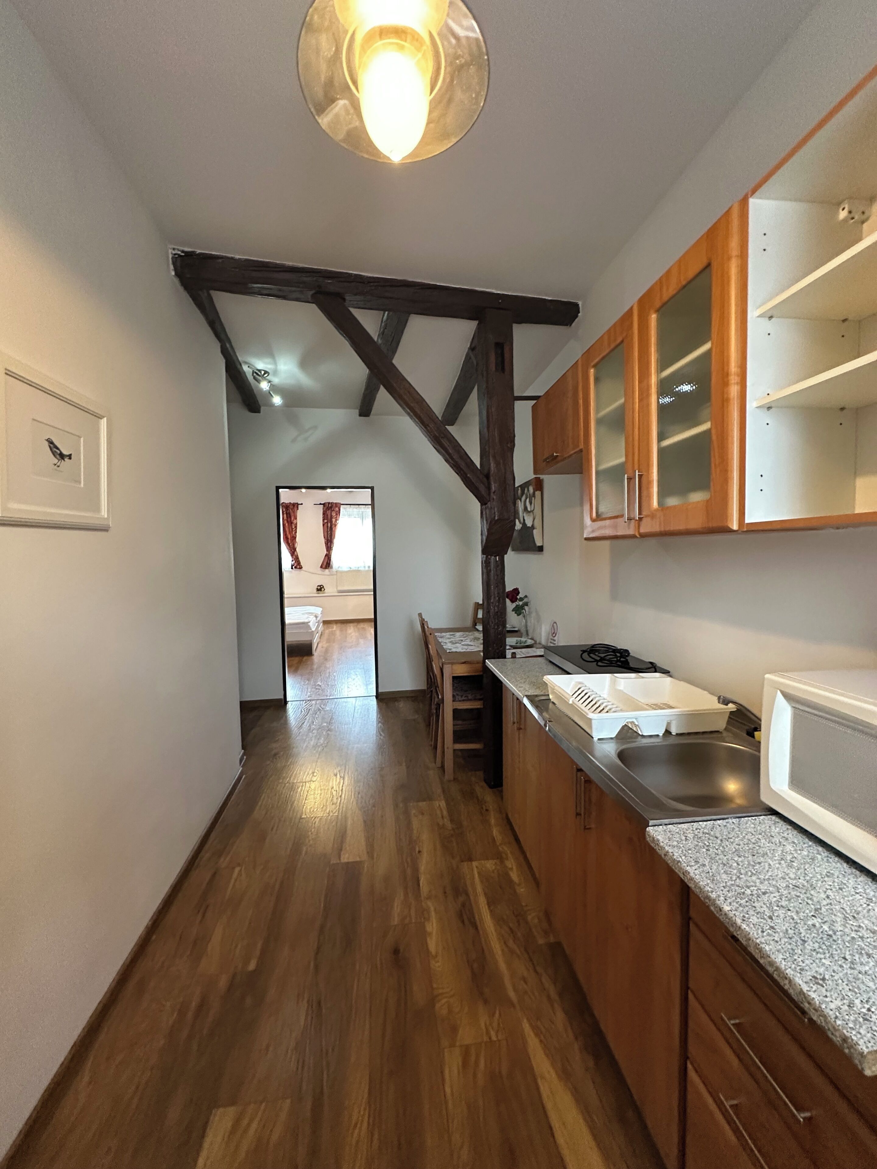 A kitchen with wooden beams, a dining area, and a view into another room.