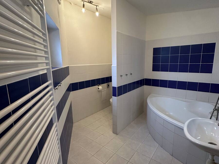 A bathroom with a bathtub, a sink, a toilet, and a shower area.