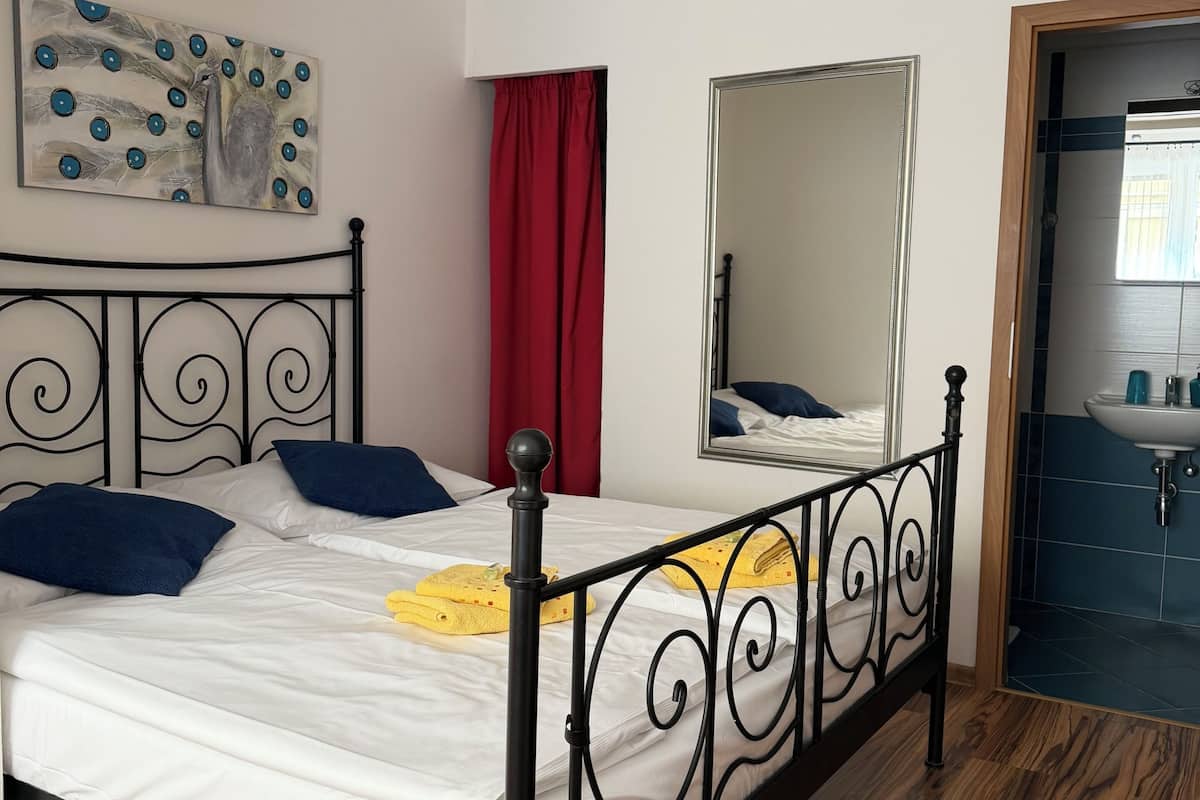 Une chambre à coucher avec un lit, un rideau rouge, un miroir et un tableau accroché au mur.