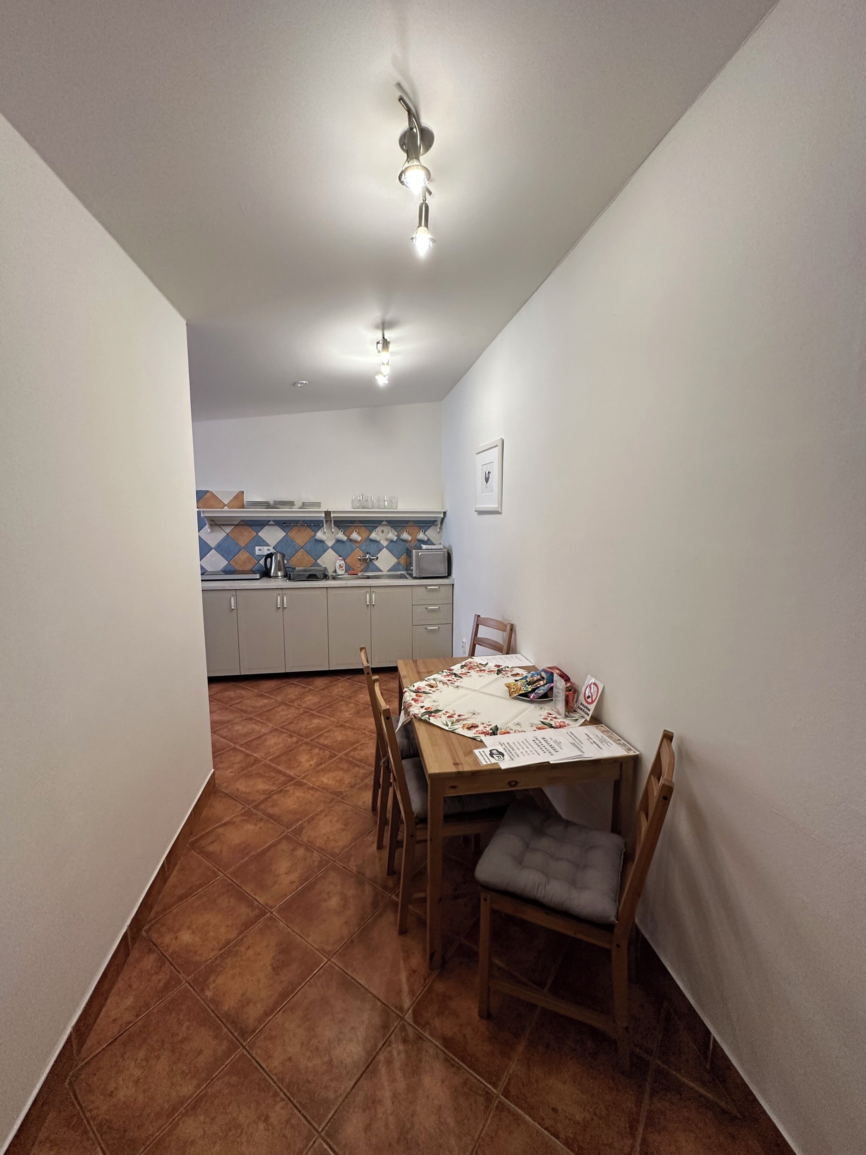 A dining area with a table, chairs, a ceiling fan, and a kitchen in the background.