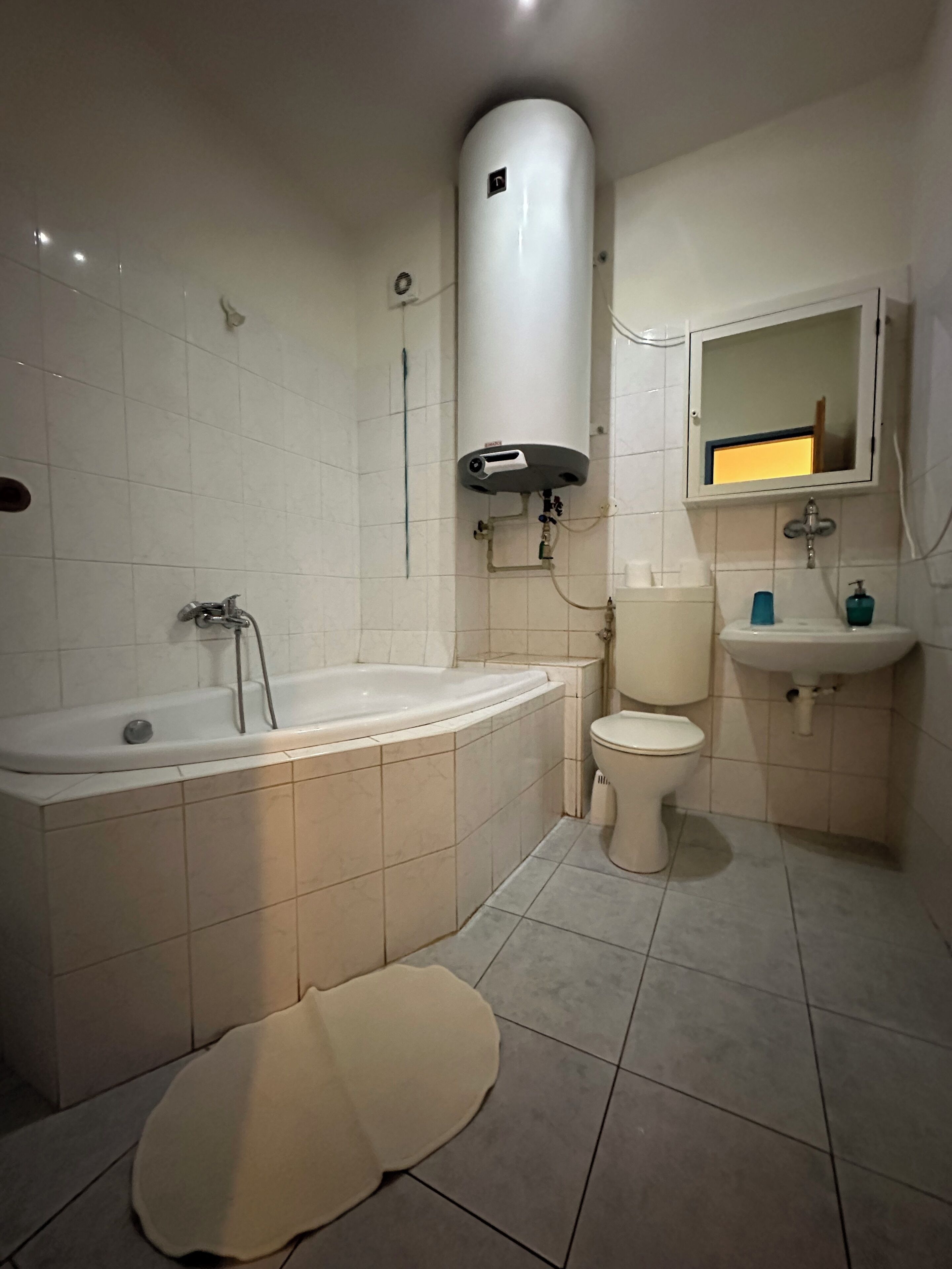 A bathroom with a bathtub, toilet, sink, and a towel warmer.