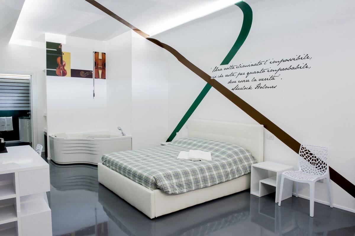 A modern bedroom with a bed, a white chair, and a wall with a quote.