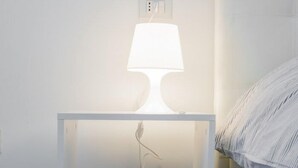 A white bedside table with a lamp, a power outlet, and a small shelf. - B&B il Castelluccio (Arezzo)