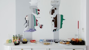 A room with a white dresser, a mirror with abstract art, and various food items on the dresser. - B&B il Castelluccio (Arezzo)