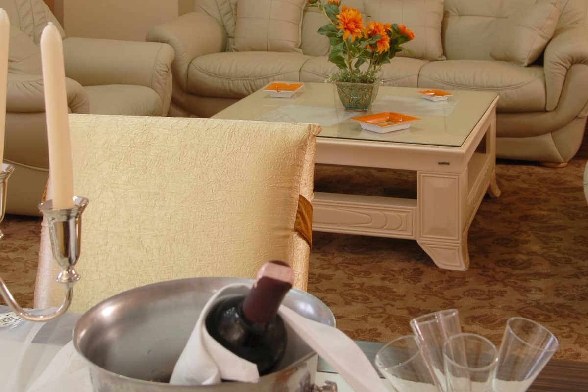 Una sala de estar con un sofá color beige, una mesa de centro de cristal y un cubo de metal con una botella.