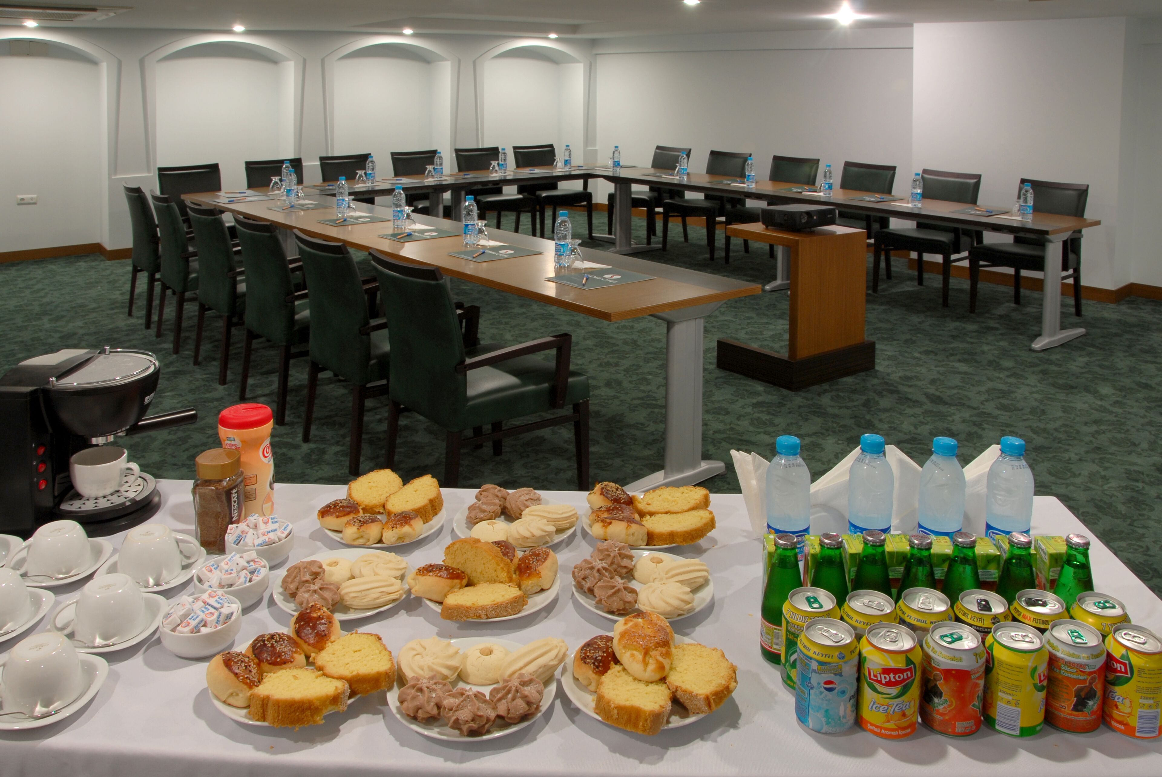 A conference room with a long table, multiple chairs, and a coffee station.