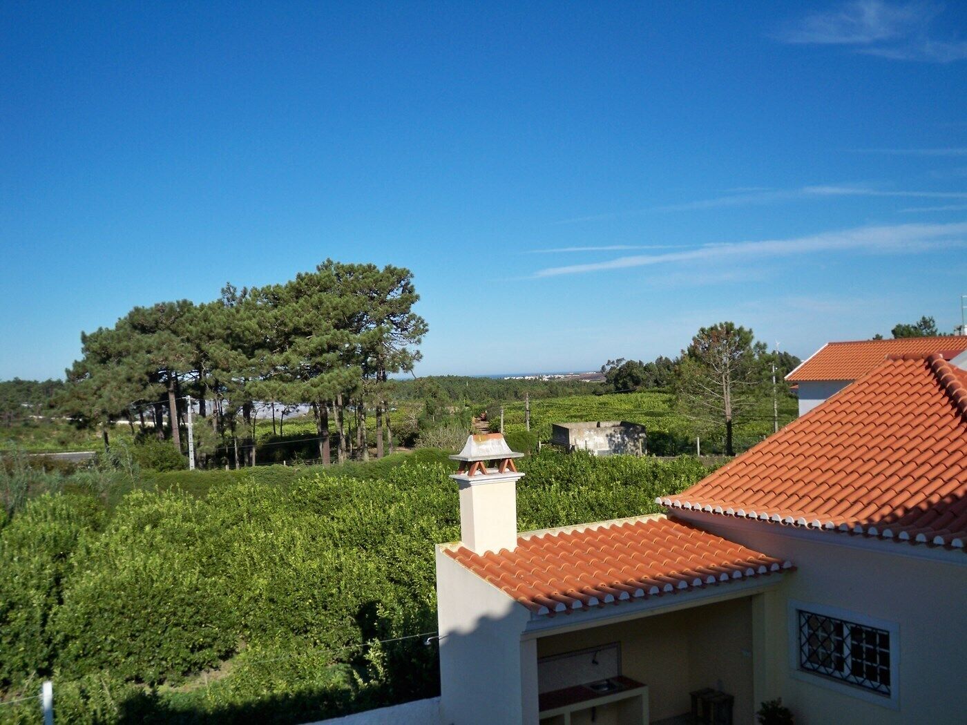 A residential area with a house featuring a red-tiled roof and a white chimney.