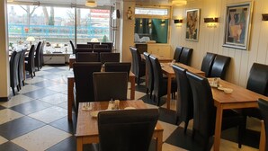 A restaurant with a checkered floor, black leather chairs, wooden tables, and pendant lighting. - Hotel Freiheit (Cologne)