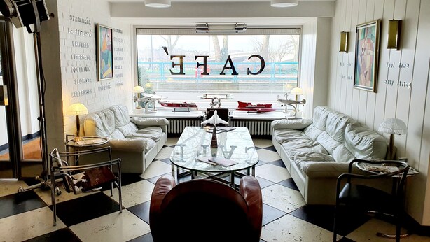 A modern living room with a large window, two white sofas, a coffee table, and a black and white checkered floor. - Hotel Freiheit (Cologne)