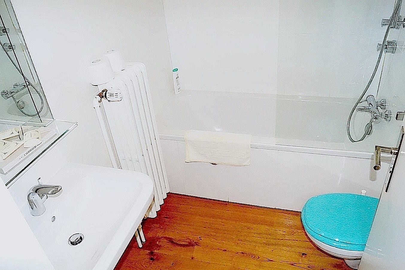A small bathroom with a white sink, a toilet, and a shower.