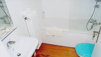A small bathroom with a white sink, a toilet, and a shower.