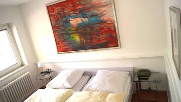 Ein Schlafzimmer mit Bett, Fenster, Heizkörper, Nachttisch, Lampe und Telefon.